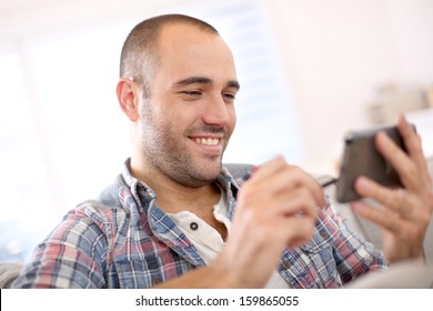 Cheerful Young Man At Home Using Smartphone