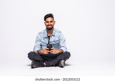 Cheerful young man sitting with legs crossed isolated over white background, using mobile phone - Powered by Shutterstock