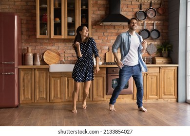 Cheerful Young Married Loving Couple Dancing To Energetic Disco Music Barefoot On Warm Heated Floor In Old Fashioned Kitchen, Celebrating Freedom Or Carefree Leisure Weekend Pastime In Own House.