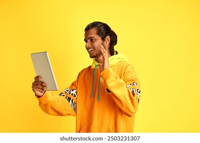 Cheerful young middle eastern man waving hello calling his friends in distance against yellow studio background. Concept of human emotions, diversity, youth, modern lifestyle, technology. Ad - Powered by Shutterstock