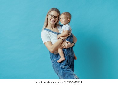 Cheerful Young Mom Posing With Her One Year Kid On Blue Background