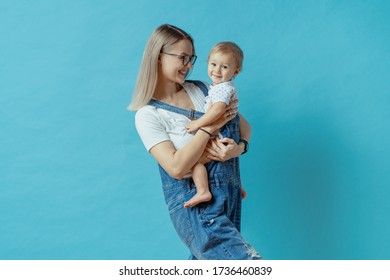 Cheerful Young Mom Posing With Her One Year Kid On Blue Background