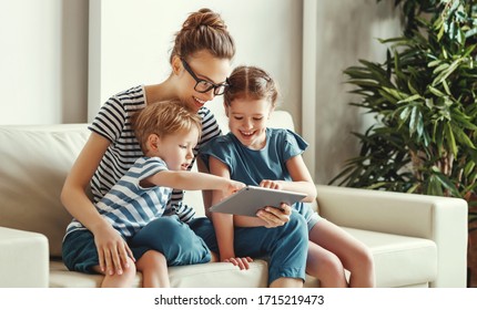 Cheerful young mother with little son and daughter sitting on sofa and playing video game on tablet while spending time together at home
 - Powered by Shutterstock