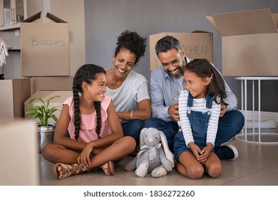 Cheerful Young Multiethnic Parents Talking And Playing With Daughters While Sitting On Floor In New House. Indian Man Family Tickles And Jokes With His Little Girl After Relocating To New Home.