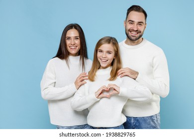 Cheerful young parents mom dad with child kid daughter teen girl in sweaters showing shape heart with hands heart-shape sign isolated on blue background studio portrait. Family day parenthood concept