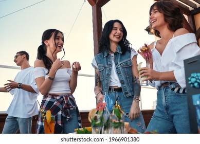 Cheerful Young People Drinking Cocktails And Talking At A Rooftop Party