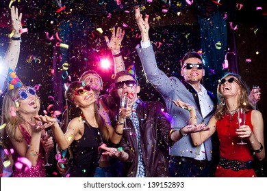 Cheerful young people showered with confetti on a club party. - Shutterstock ID 139152893