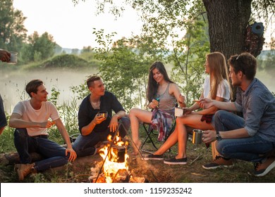 cheerful young people warming near the camp fire. warmth concept. unforgettable moments with best friends - Powered by Shutterstock