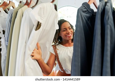 Cheerful Young Pretty Black Woman Looking Through Clothes On The Rack