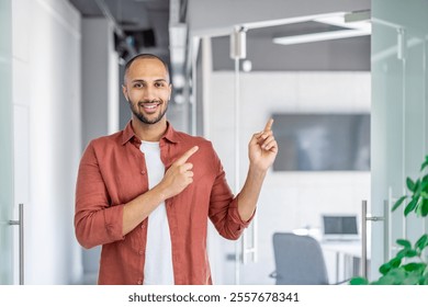 A cheerful young professional in a casual outfit points towards a doorway in a bright office space, symbolizing guidance, professionalism, and enthusiasm. - Powered by Shutterstock