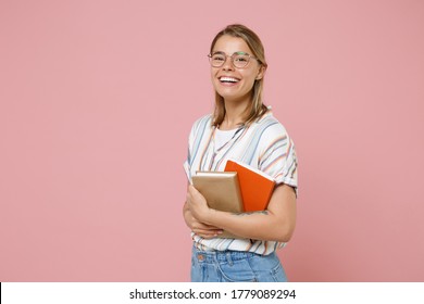 Cheerful Young Student Girl In Casual Striped Shirt Eyeglasses Posing Isolated On Pink Background Studio Portrait. Education In High School University College Concept. Mock Up Copy Space. Hold Books