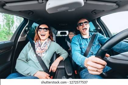  Cheerful Young Traditional Family Has A Long Auto Journey And Singing Aloud The Favorite Song Together. Safety Riding Car Concept Wide Angle Inside Car View Image. 