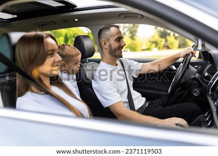 Cheerful young traditional family has a long auto journey and singing aloud the favorite song together. Safety riding car concept wide angle inside car view image.