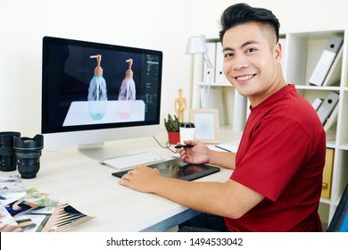 Cheerful young Vietnamese professional 3D designer working on graphic tablet on visualization for commercial project - Powered by Shutterstock