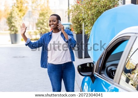Cheerful young woman with car troubles calling for roadside assistance - Insurance concepts. Young African American woman calling a car repair service after car breakdown