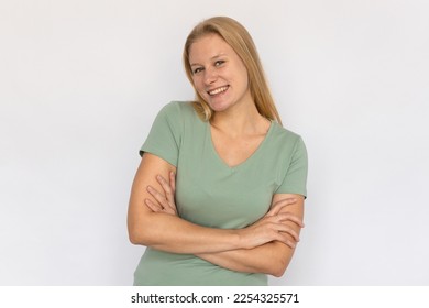 Cheerful young woman crossing arms. Portrait of happy Caucasian female model with fair hair in green T-shirt looking at camera, smiling, proud of herself. Happiness, success concept - Shutterstock ID 2254325571