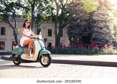 Cheerful Young Woman Driving Scooter In Town