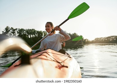 Cheerful young woman enjoying kayaking with her friend in a lake on a summer day. Kayaking, travel, leisure concept