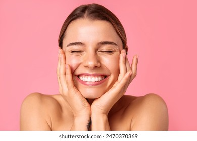 A cheerful young woman flashes a bright smile against a pink backdrop, showcasing her clear, radiant skin and natural beauty. Perfect for wellness, skincare, and positivity concepts. - Powered by Shutterstock