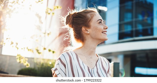 Cheerful Young Woman With Freckles And Red Hair Posing Against The Sunshine And Smile Looking Up