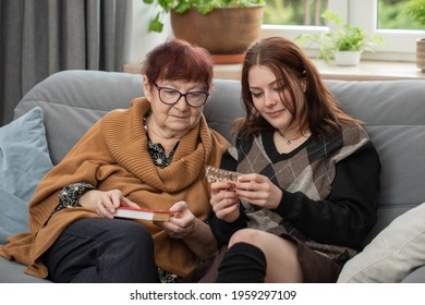 cheerful young woman helping an elderly woman with pills medical prescription. teenager showing elderly female how to use weekly pill organizer with different kind of pills