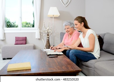 Cheerful Young Woman Helping An Old Person Doing Paperwork And Telephone Call