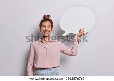 Cheerful young woman holding communication bubble she invites your message to take center stage creating ideal setting to captivate audience with your brands story wears elegant shirt and jeans