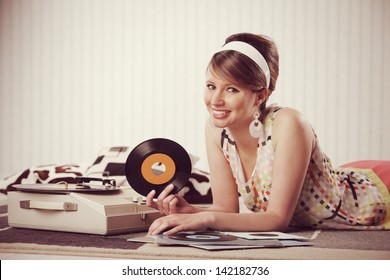 A cheerful young woman listening to a record