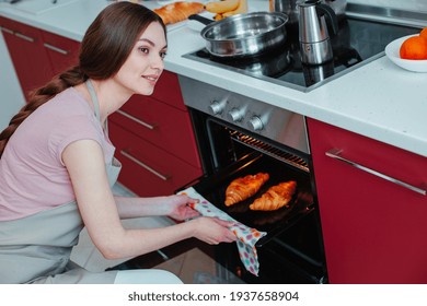 Cheerful Young Woman Looking Away While Holding A Baking Pan With A Towel