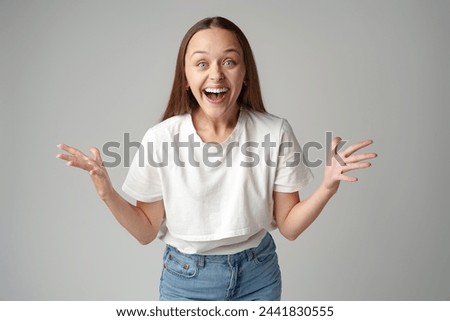 Cheerful young woman looking at camera smiling laughing over gray background