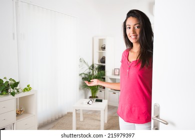 Cheerful Young Woman Opening Her House Front Door And Inviting Friends At Home 