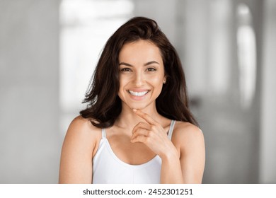 A cheerful young woman with a radiant smile posing confidently, looking at the camera with a blurred background - Powered by Shutterstock