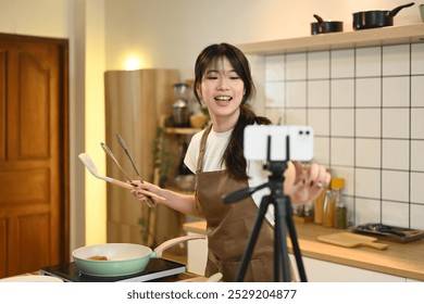 Cheerful young woman recording a cooking tutorial in a modern kitchen - Powered by Shutterstock