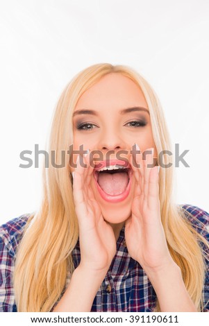 Cheerful young woman in shirt holding hands near mouth and shouting