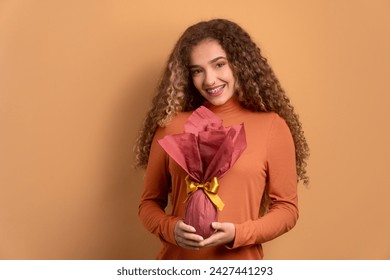 cheerful young woman showing easter egg in beige colors. holiday, easter, celebration concept.