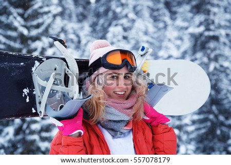 Cheerful young woman with a snowboard. Woman stands against a background of snow-covered trees