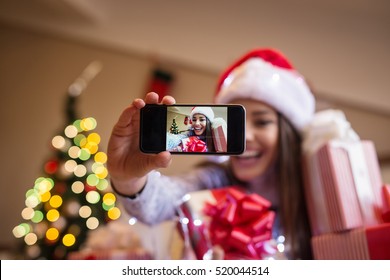 Cheerful Young Woman Taking A Christmas Selfie With Smartphone.