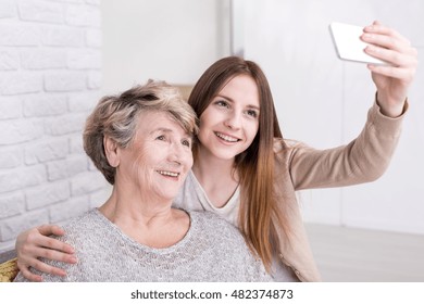 Cheerful young woman taking selfie photo of herself and her grandmother - Powered by Shutterstock