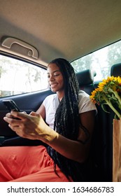 Cheerful Young Woman Texting Friends When Riding Home On Backseat Of Taxi Car