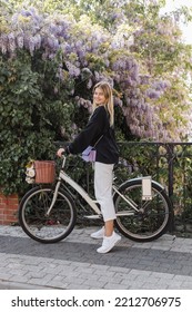 Cheerful Young Woman In Trendy Outfit Near Bicycle And Blooming Tree In Turkey