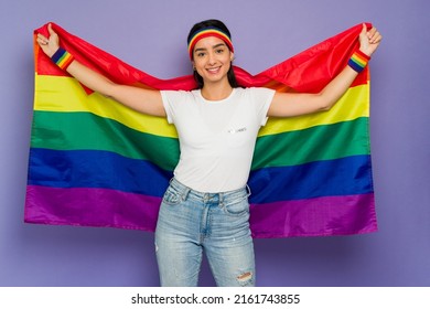 Cheerful Young Woman Using A Pride Rainbow Flag To Support Gay Rights During A LGBT March 