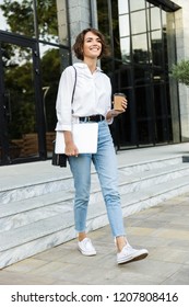 Cheerful Young Woman Walking Outdoors At The Street, Carrying Laptop Computer