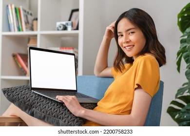 Cheerful Young Woman Wear Orange Shirt With Sitting On Sofa And Using Laptop Computer At Home.