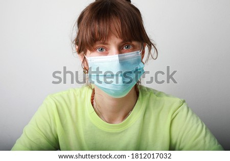Cheerful young woman wearing medical mask sitting at her workplace. Space for text.
