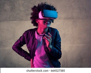 Cheerful Young Woman Wearing VR Goggles On The Concrete Background.