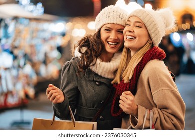 Cheerful young women friends at christmas time are having fun and shopping presents for their family