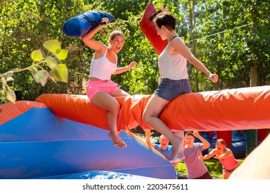 Cheerful Young Women Having Fun On Inflatable Pillow Fight Arena In Outdoor Amusement Park On Sunny Summer Day..