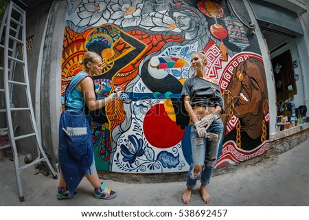 Cheerful young women painting on the wall.