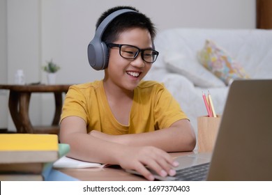 Cheerfully Boy Excited Using Computer Online Learning Schoolwork. Asian Boy Enjoy Self Study With E-learning At Home. Online Education And Self Study And Homeschooling Concept.