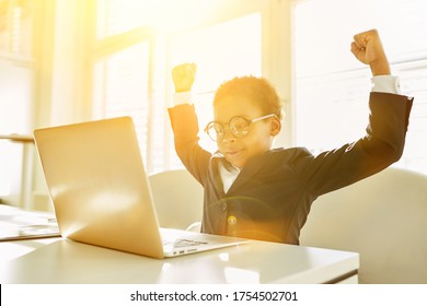 Cheering African Kid As A Business Manager In Front Of Laptop Computer In The Office